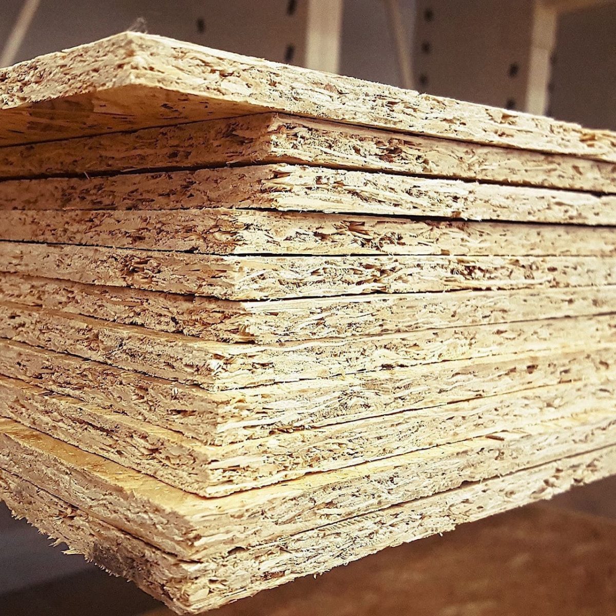 Ein Stapel OSB-Platten auf einem Regal, der die geschichteten Kanten der Holzwerkstoffplatten zeigt.